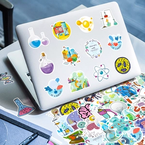 Detailed view of colorful cartoon science lab stickers applied to a silver laptop surface