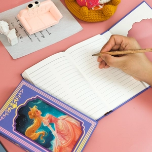 Detailed close-up of a purple princess notebook with ruled pages and a wooden pencil