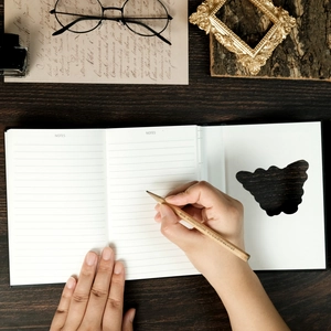 Detail of lined notebook pages with butterfly motifs and a pencil on a wooden desk