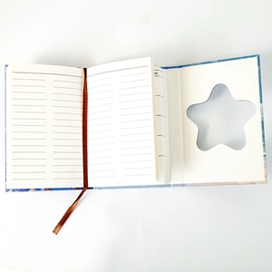 Detail view of the open notebook with ruled pages, ribbon bookmark, and star cutout