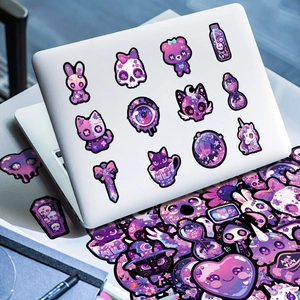 Macro view of dark purple gothic stickers with skulls and cats on a laptop surface