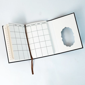 Detail view of black hardcover notebook with calendar grid pages and brown ribbon bookmark