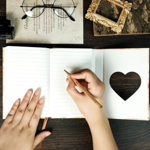 Notebook detail with heart-shaped cutout and lined pages on dark wooden background