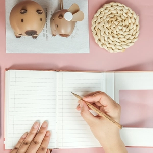 Close-up of lined notebook pages with a natural wood pencil on a pink surface