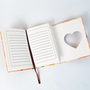 Detail of pink floral notebook featuring heart-shaped cutout and brown silk bookmark