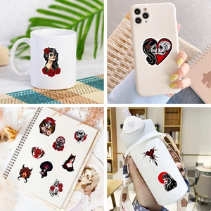Gothic stickers on laptop and water bottle showing dark red rose and skull designs