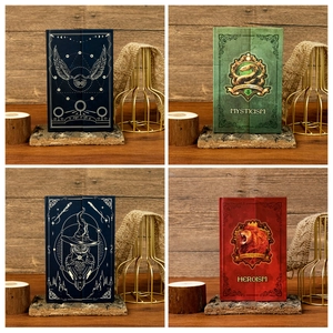 Detail of four magic themed notebooks with vintage mystical emblems on dark wood background
