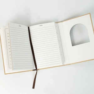 Detail of vintage notebook with lined pages, fabric bookmark, and arched cutout window