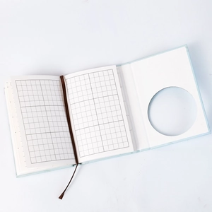 Detail view of the light blue notebook with grid paper and brown ribbon bookmark