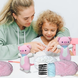 Detailed DIY crochet kit with pink pig plush, yarn, needles, and step-by-step instructions