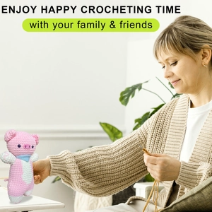 Woman crocheting a pink flying pig plushie with yarn and hook in a cozy indoor setting