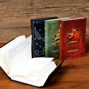 Detail of magic academy themed hardback notebooks with gold lion and snake crests