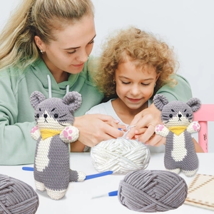 Close-up of handmade crochet cat dolls with vibrant yarn balls and crafting tools