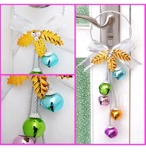 Detalle de campanas navideñas de metal de colores con lazo plateado y hojas de acebo