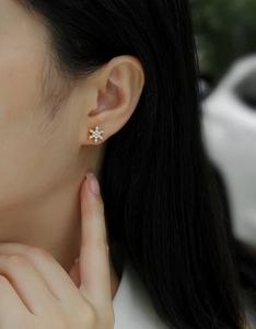 Detailed close-up of S925 silver snowflake stud earrings with 18k gold plating on ear