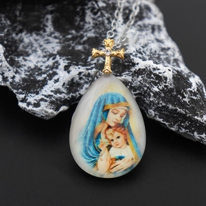 Macro shot of Virgin Mary religious pendant with golden cross and silver chain necklace