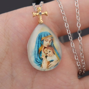 Macro detail of teardrop religious pendant with Madonna icon and gold cross bail