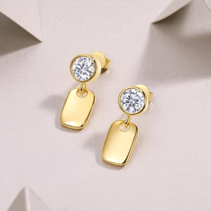 Macro detail of S925 sterling silver gold earrings with round moissanite and rectangular pendant