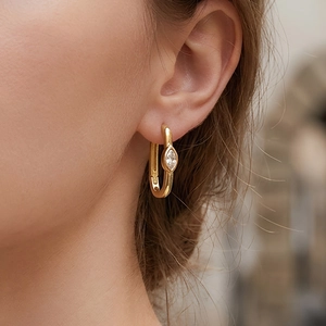 U-shaped gold hoop earrings with marquise-cut white stone on a female model