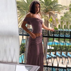 Detail of fuchsia polka dot two-piece set with off-shoulder crop top and tiered maxi skirt