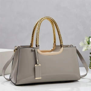 Grey patent leather handbag featuring a sophisticated gold woven handle and long shoulder strap