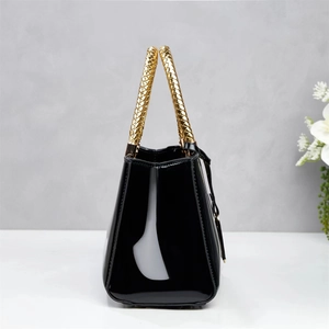 Detail showing high-gloss black patent leather texture and gold snakeskin handle