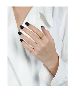 Close-up of golden bow open ring and crystal bands stacked on hand with black nails