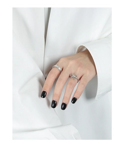 Detail of silver bow ring and textured band on model's hand with black nail polish