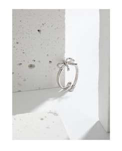 Close-up of elegant S925 sterling silver bow ring on a white minimalist stone base