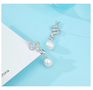 Detail of 925 silver snake earrings with green zircon eyes and white pearls