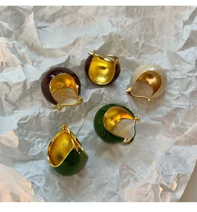 Detail view of colorful retro enamel hoop earrings in green, red, and cream tones