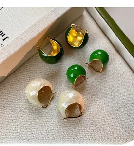 Close-up of vintage enamel C-shaped stud earrings in green and white with gold finish