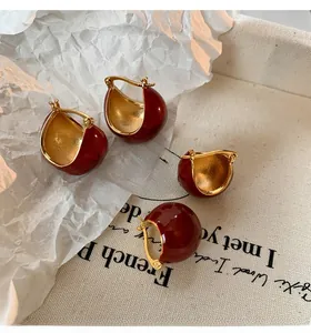 Detail of red enamel hoop earrings with gold-plated interior on vintage canvas