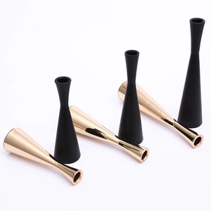 Modern minimalist metal candle holder set in matte black and gold finishes on white