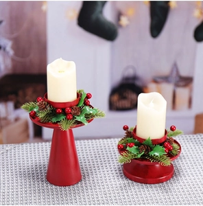 Nahaufnahme von roten Weihnachts-Kerzenhaltern mit Kiefernnadeln und Beeren-Dekor