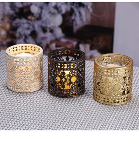 Detailansicht von drei Vintage-Metall-Kerzenhaltern mit floralen Mustern in Gold und Bronze
