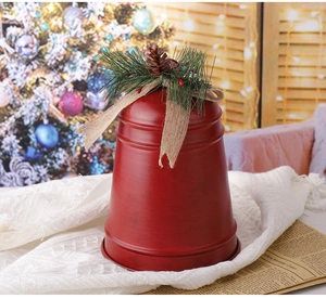Detail der roten Metall-Weihnachtsglocke mit Tannenzapfen und Leinenschleife auf Tuch