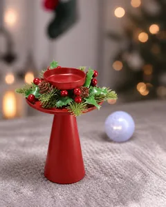 Detail eines roten Weihnachtskerzenhalters mit künstlichen Tannennadeln, Beeren und Zapfen