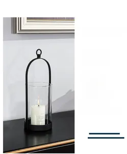 Detail of a black iron candle holder with clear glass shade and warm burning candle