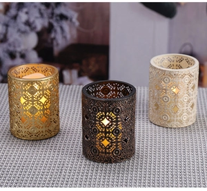 Detailansicht hohler Metallkerzenhalter in Gold, Bronze und Cremeweiß mit Mustern