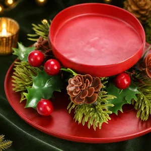 Detail eines Weihnachts-Kerzenhalters mit rotem Metallgefäß, Kiefernzapfen und Beeren