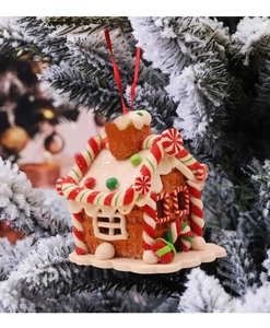 Detailansicht eines Lebkuchenhaus-Weihnachtsanhängers an einem verschneiten Tannenzweig