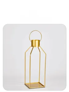 Detail view of a modern gold geometric metal candle holder with a top handle and matte finish