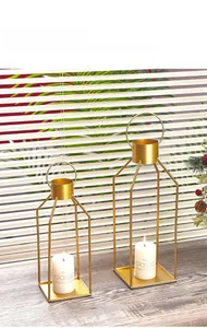 Detail of geometric gold iron candle holders in two sizes on a rustic wooden table