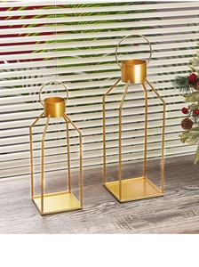 Close-up of dual gold geometric wire candle holders with square bases and round cups