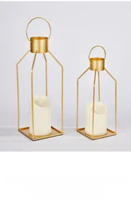 Detail view of two gold geometric metal candle holders with white pillar candles inside