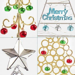 Mini-Weihnachtsbaum aus Metall mit bunten Glocken und Merry Christmas Schild auf Weiß