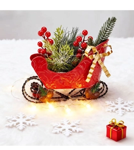 Close-up of a festive red sleigh decor with green pine needles and red berries