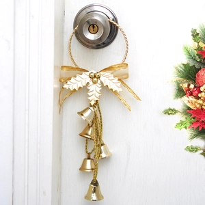 Nahaufnahme von goldenen Weihnachtsglocken mit Schleife an einem weißen Türgriff