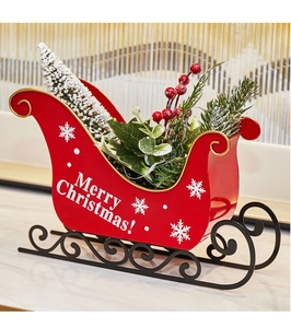 Detailed view of red Christmas sleigh decor with miniature tree and gold accents
